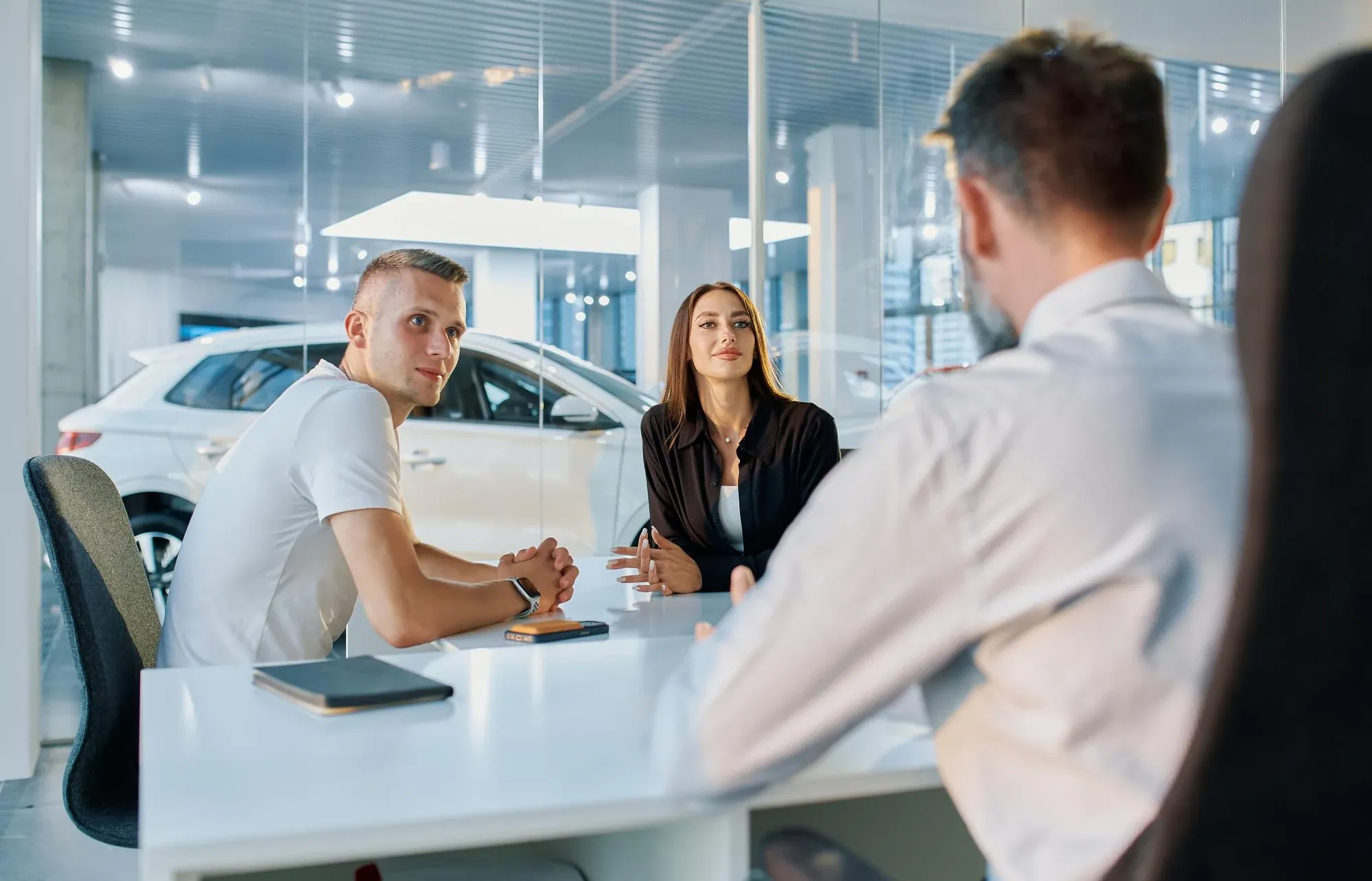 A salesperson sitting down with a couple at a desk in a showroom