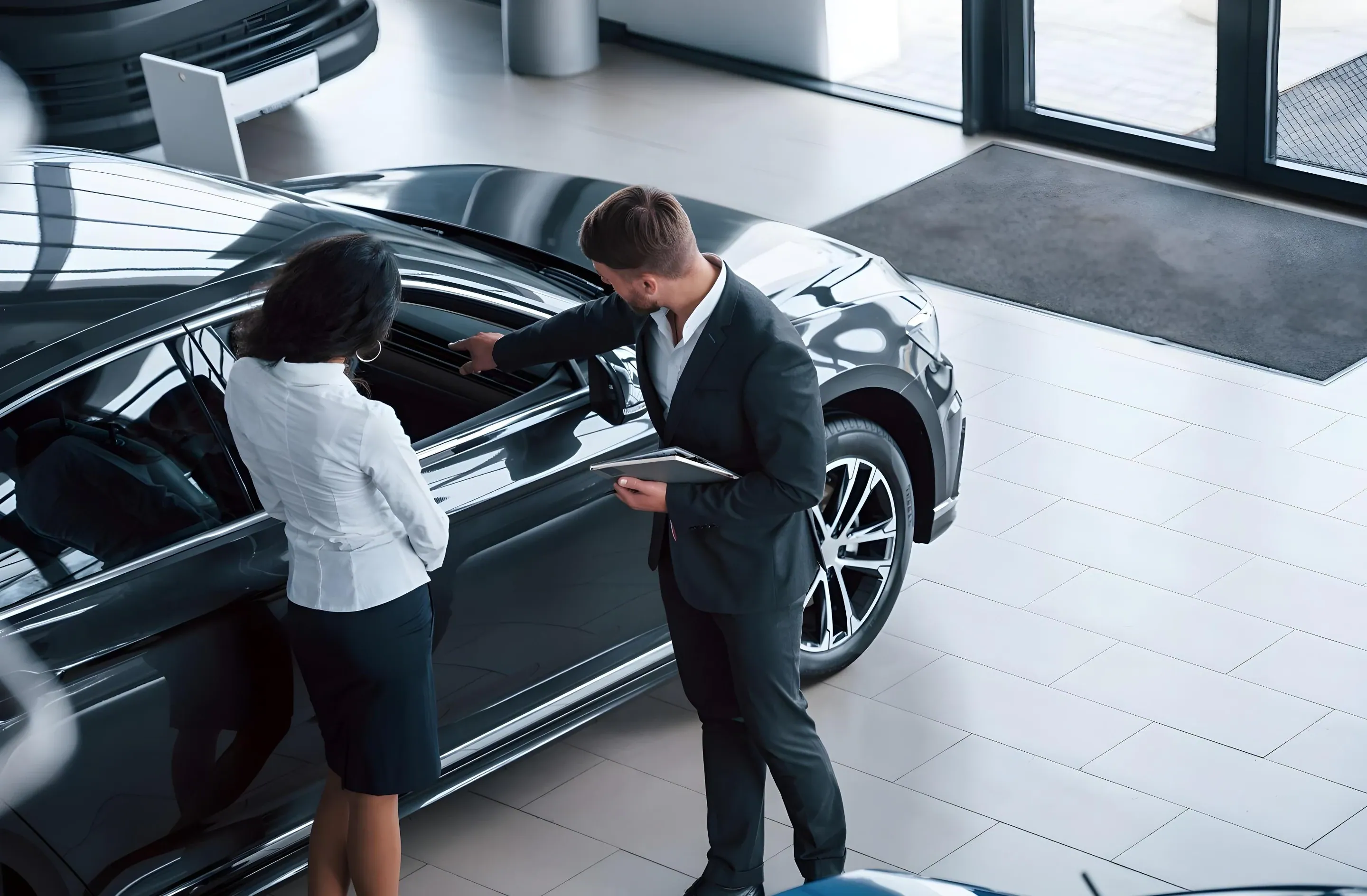 A salesperson opening a car door for a buyer in a showroom